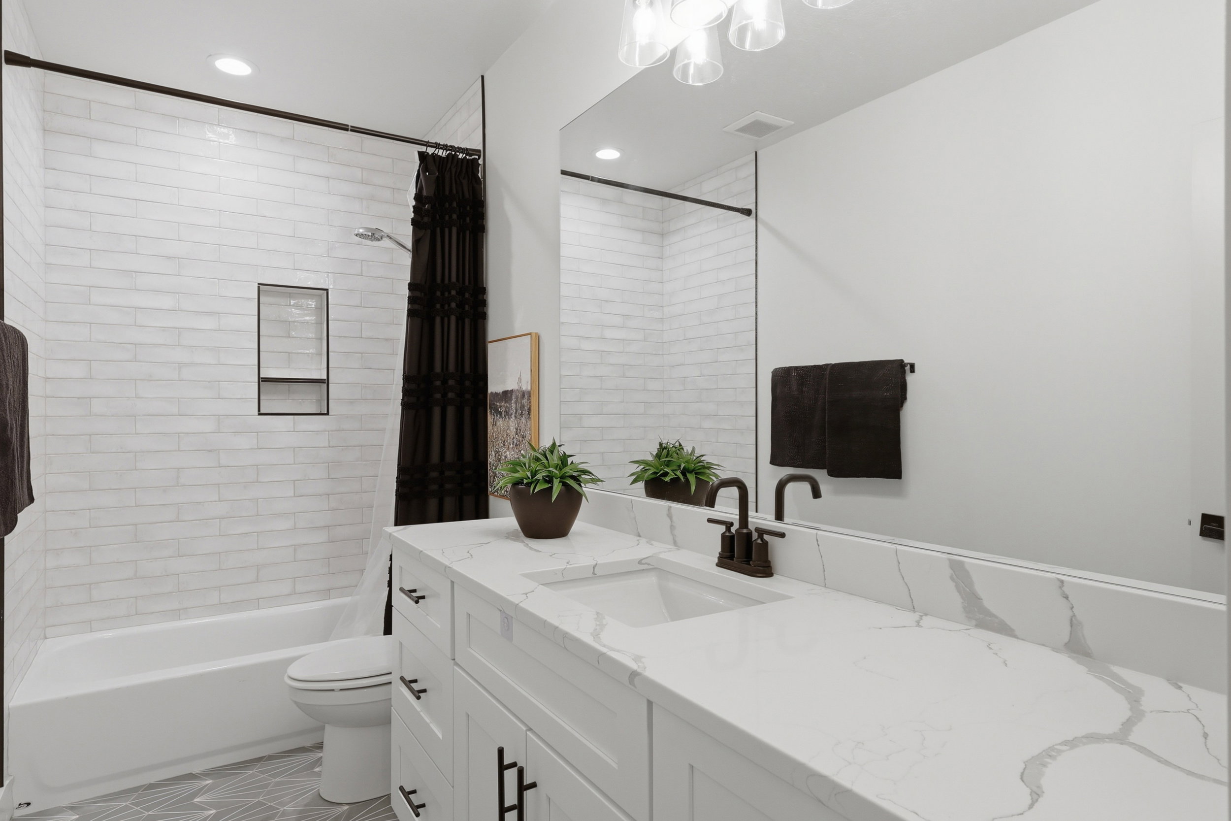 Bathroom featuring a white subway tile shower surround with a built-in niche, a white tub, and a vanity with a white countertop