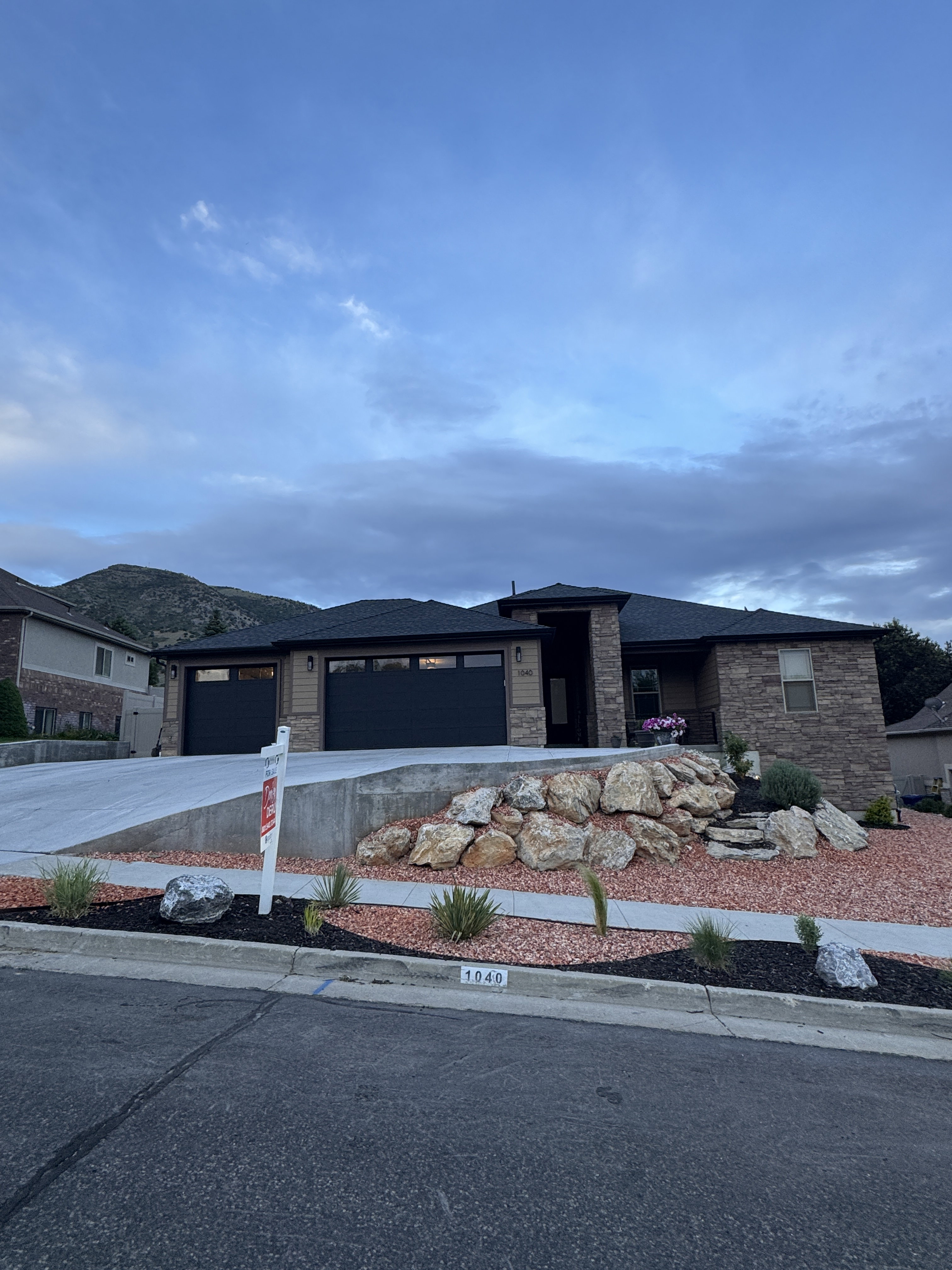 Contemporary ranch-style residence featuring stone and horizontal siding accents, a paved driveway, and a two-car garage