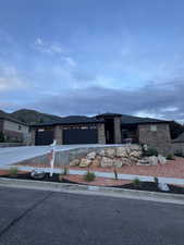Contemporary ranch-style residence featuring stone and horizontal siding accents, a paved driveway, and a two-car garage