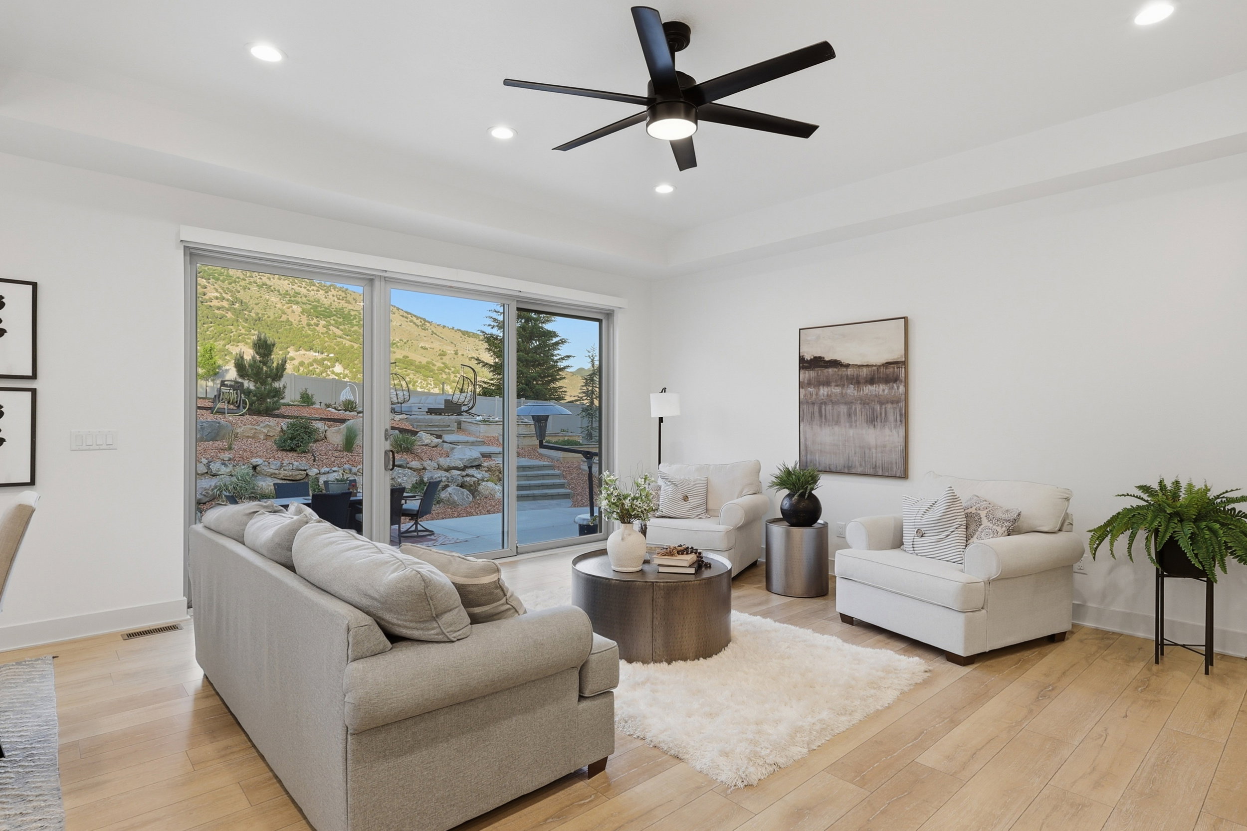 Spacious living area with views featuring light wood-finish flooring, a contemporary ceiling fan with integrated lighting, and recessed lighting