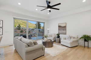 Spacious living area with views featuring light wood-finish flooring, a contemporary ceiling fan with integrated lighting, and recessed lighting