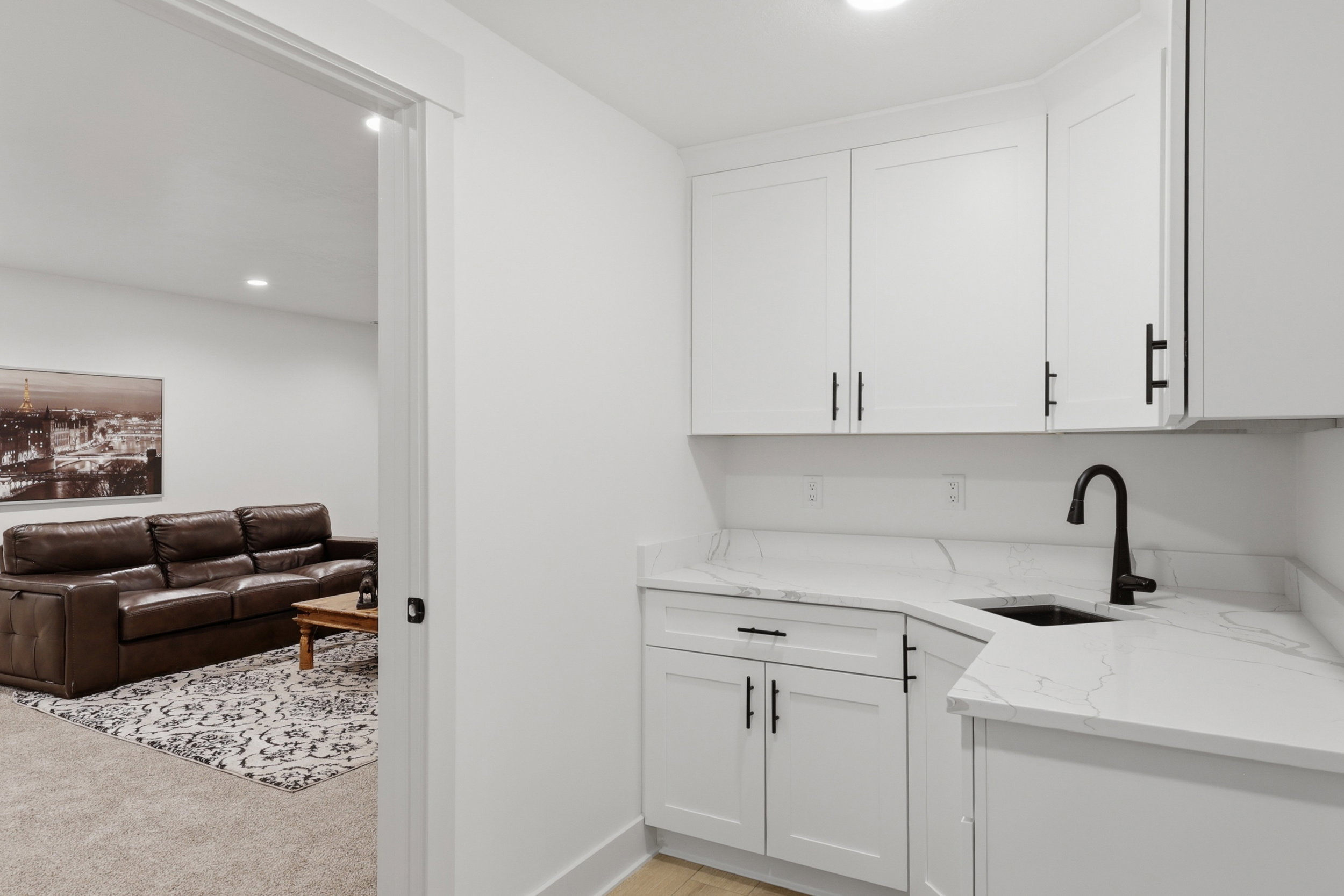 Wet bar featuring white shaker cabinetry, white countertops, black sink, and a black gooseneck faucet