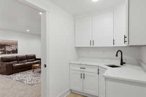 Wet bar featuring white shaker cabinetry, white countertops, black sink, and a black gooseneck faucet