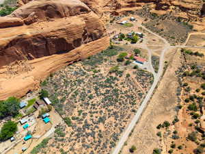 Expansive property nestled against a natural rock formation, featuring multiple buildings, unpaved roadways, and native vegetation