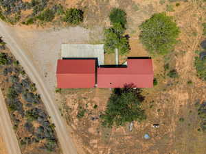 Property featuring a red metal roof, concrete patio, and mature trees on a natural landscape