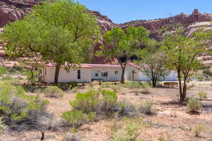White single-story residence with a red roof, surrounded by mature green trees and desert landscaping