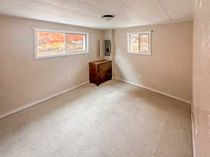 Neutral-toned room featuring two windows, light-colored flooring, and a flush-mount ceiling light fixture