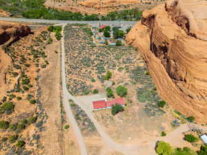 Sprawling desert property featuring a single-story residence with a red roof, a separate outbuilding, and natural rock formations