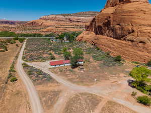 Expansive desert property featuring a white-sided building with a red roof, multiple dirt access roads, and natural rock formations