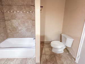 Full bathtub with a chrome shower head and tiled surround