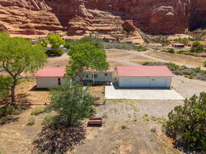 Property featuring a detached garage with an expansive concrete pad, a white exterior, and a red metal roof