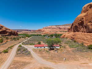 Rural property featuring a white residence with red roofing, surrounded by expansive desert landscaping