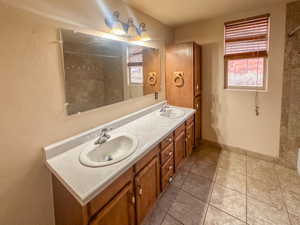 Dual vanity with light-toned countertop, wood-finish cabinetry, and integrated sinks