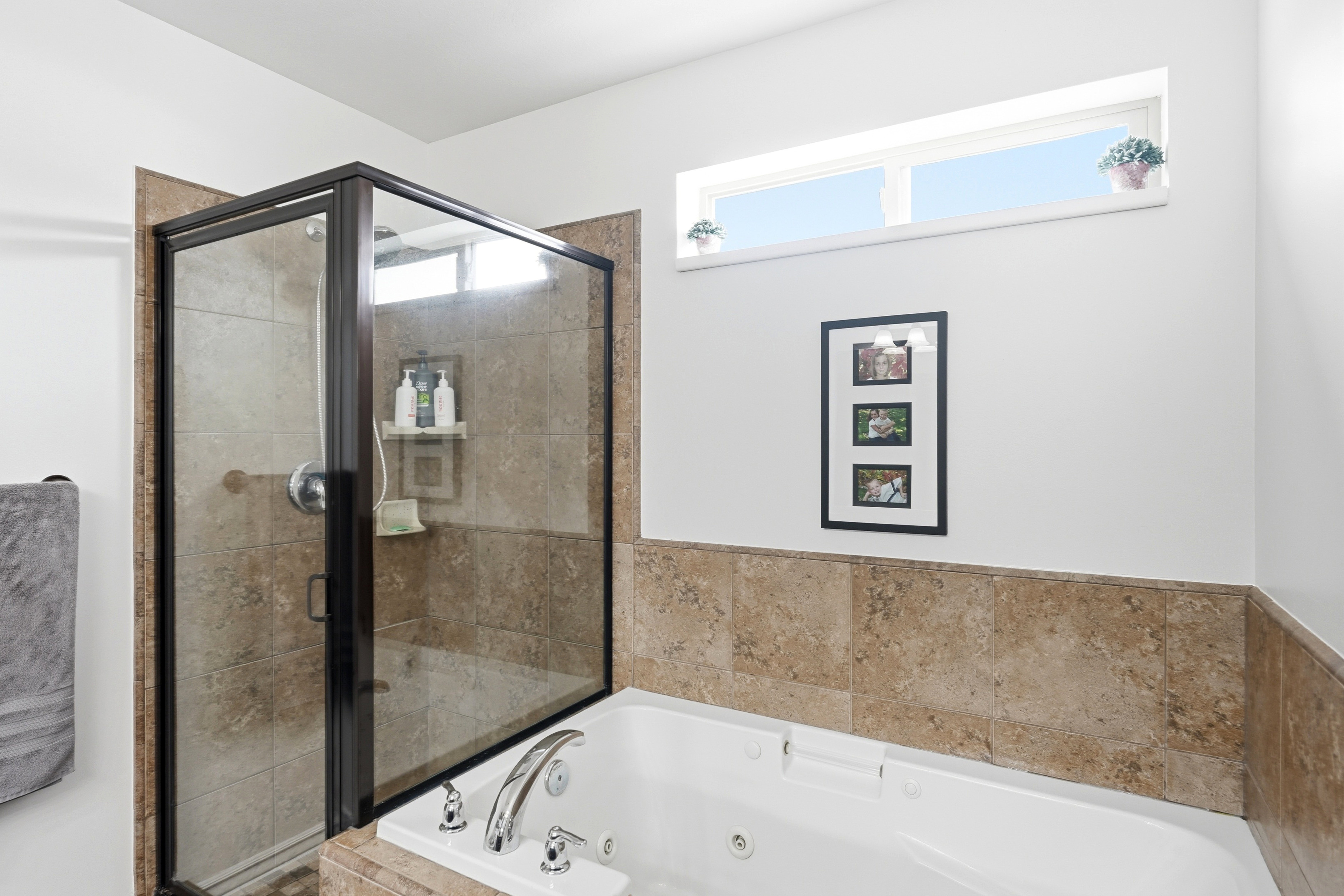 Master bathroom featuring a glass-enclosed shower with tiled walls and a jetted tub