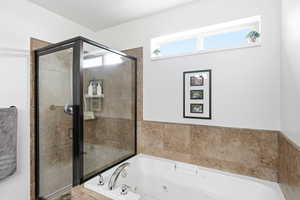 Master bathroom featuring a glass-enclosed shower with tiled walls and a jetted tub