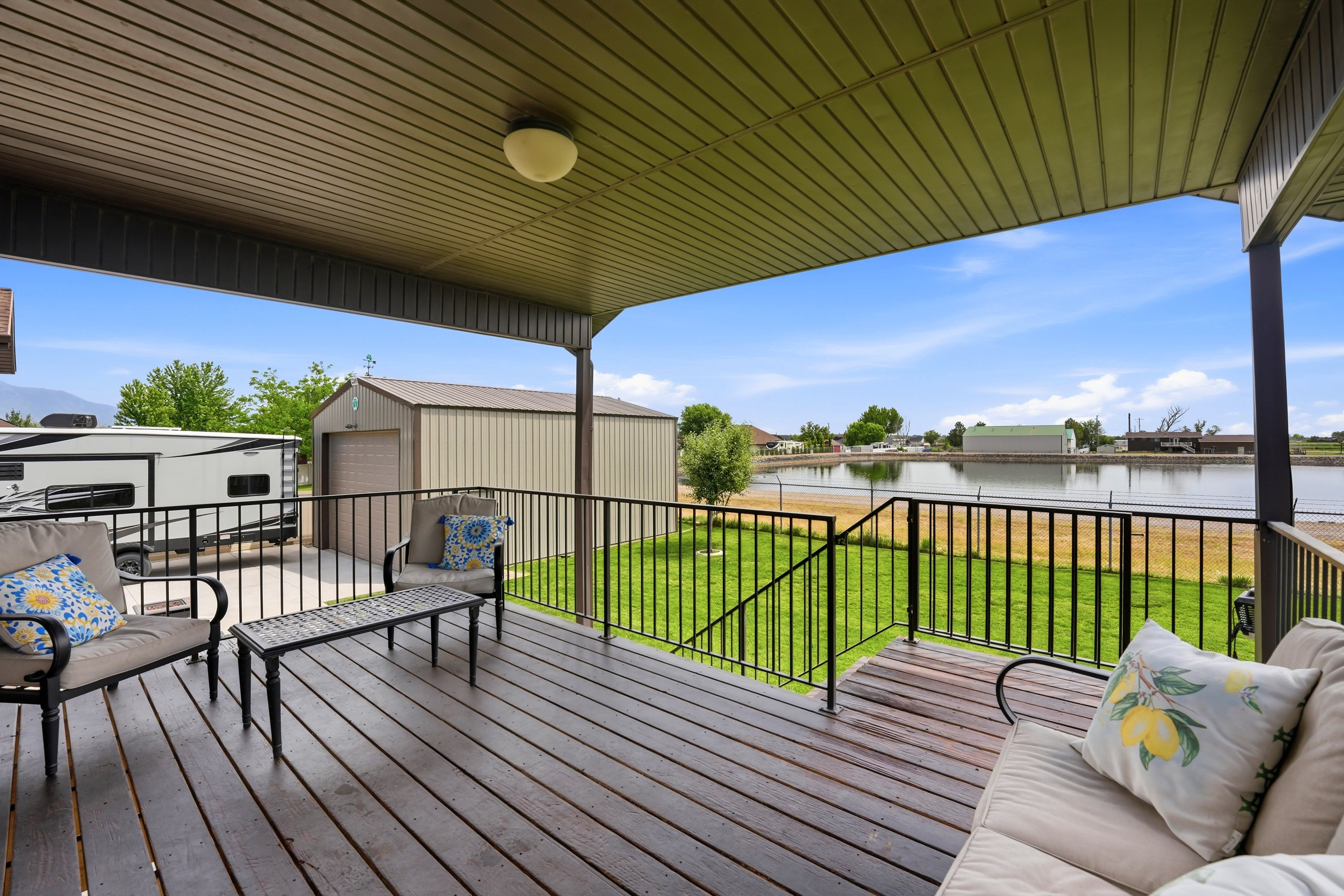 Covered outdoor deck with wood-finish flooring, black metal railings, and an overhead light fixture