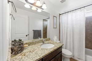 Bathroom featuring a single vanity with a granite countertop, undermount sink, and dark wood cabinetry