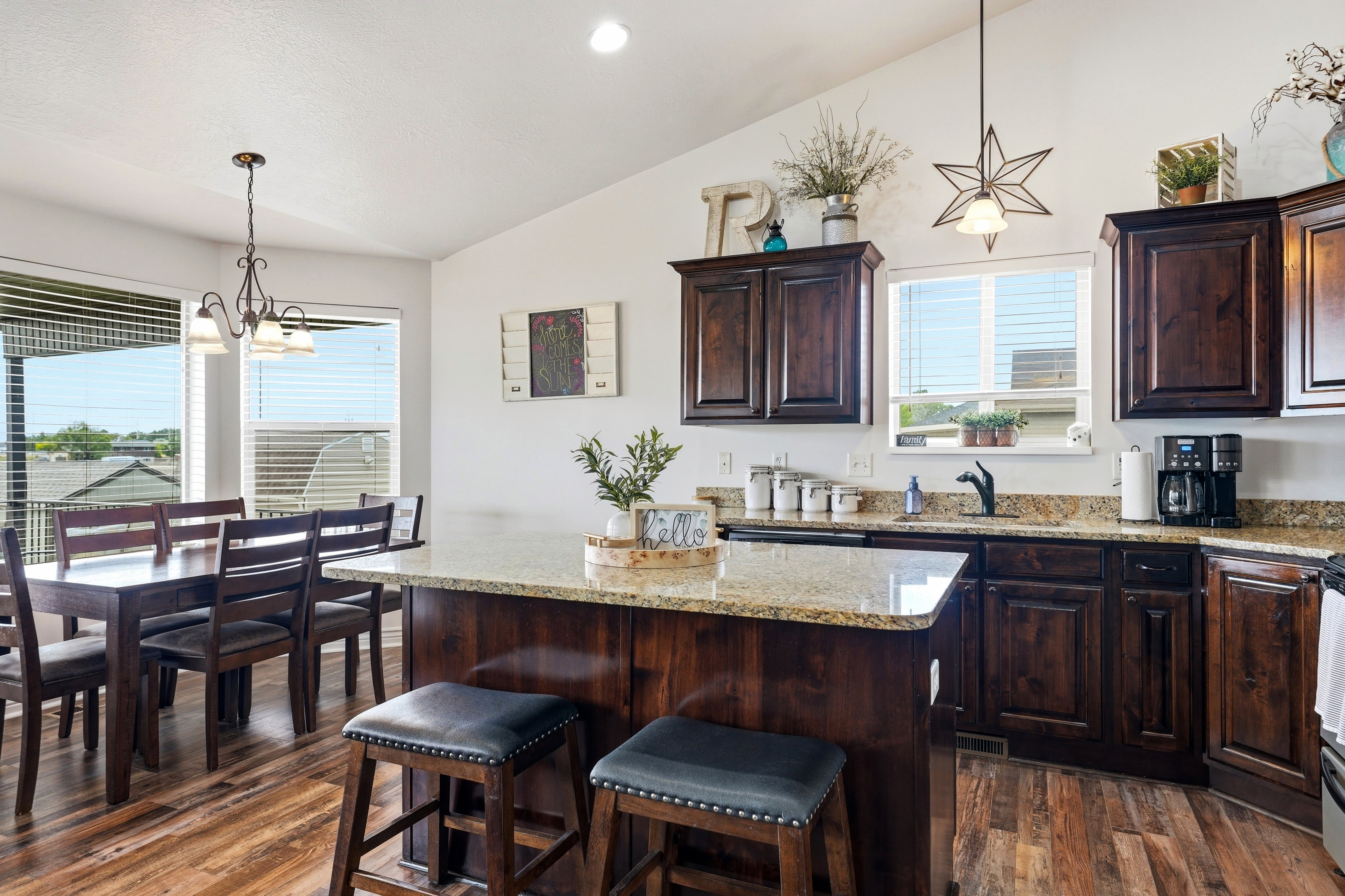 Open-concept kitchen featuring wood-finish flooring, dark wood cabinetry, and granite countertops