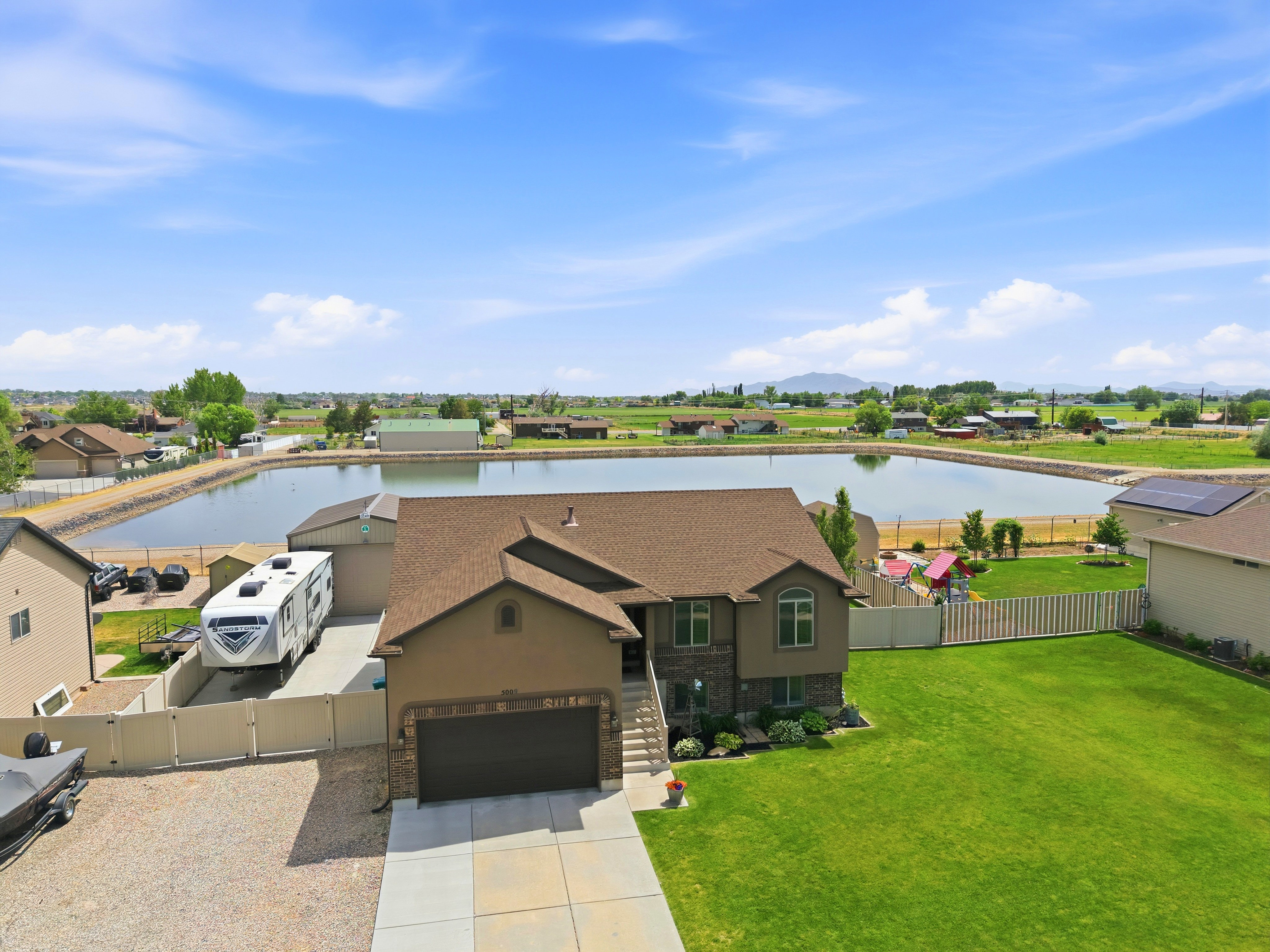Exterior residence featuring a rambler story design with a two-car garage, partial stone facade, and a well-maintained front lawn