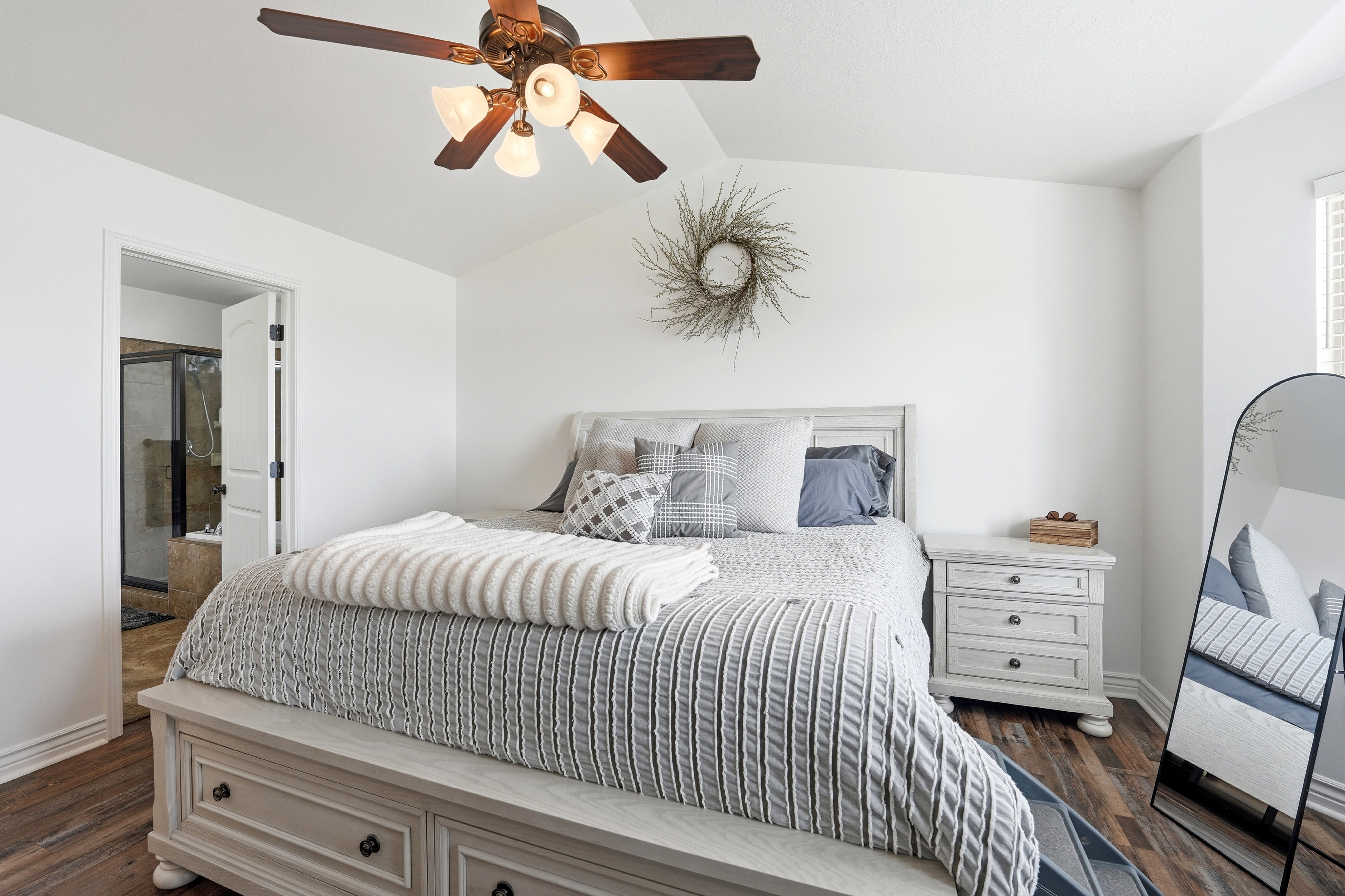 Spacious master bedroom featuring wood-finish flooring and a vaulted ceiling with a built-in ceiling fan