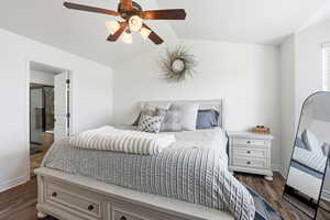 Spacious master bedroom featuring wood-finish flooring and a vaulted ceiling with a built-in ceiling fan