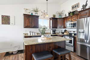 Kitchen island featuring a light-toned granite countertop and dark wood-finish cabinetry