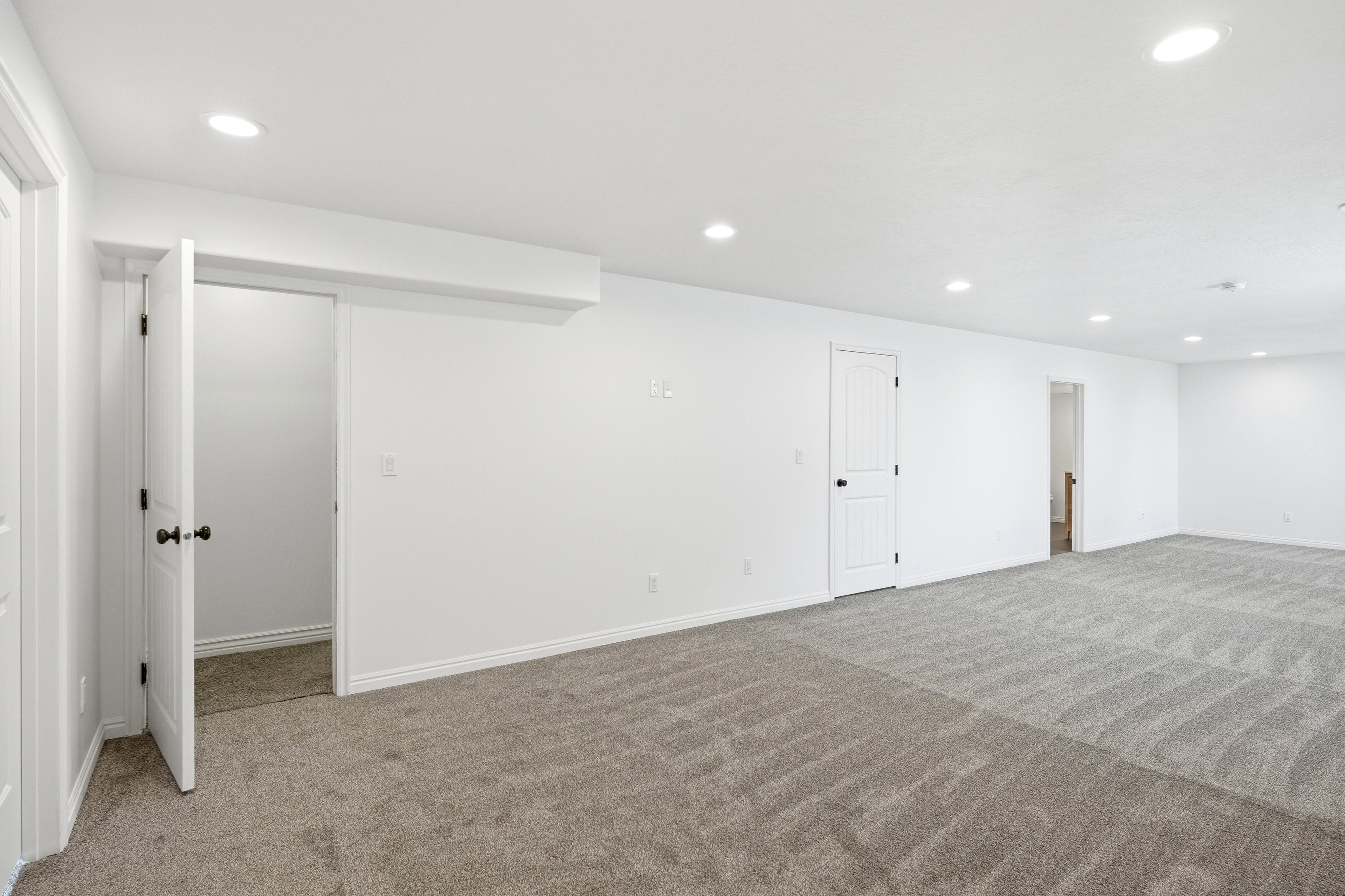 Expansive room featuring new plush gray carpet, white walls, and recessed lighting