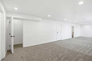 Expansive room featuring new plush gray carpet, white walls, and recessed lighting