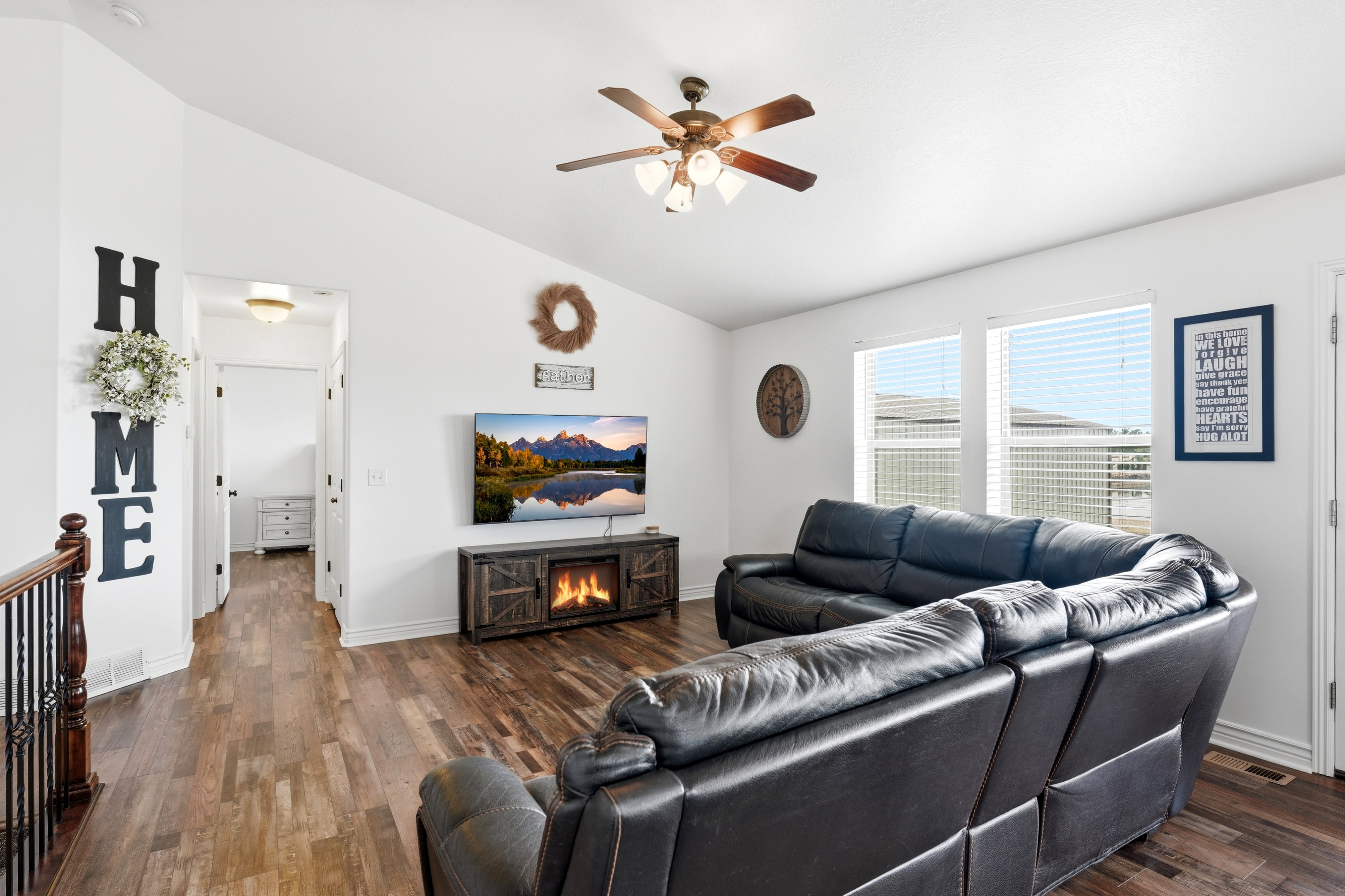 Spacious living area featuring vaulted ceilings, wood-finish flooring, and multiple windows