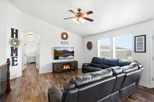 Spacious living area featuring vaulted ceilings, wood-finish flooring, and multiple windows