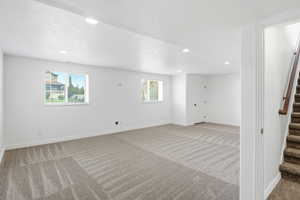 Spacious lower-level bedroom featuring carpet flooring, recessed lighting, and two windows with blinds