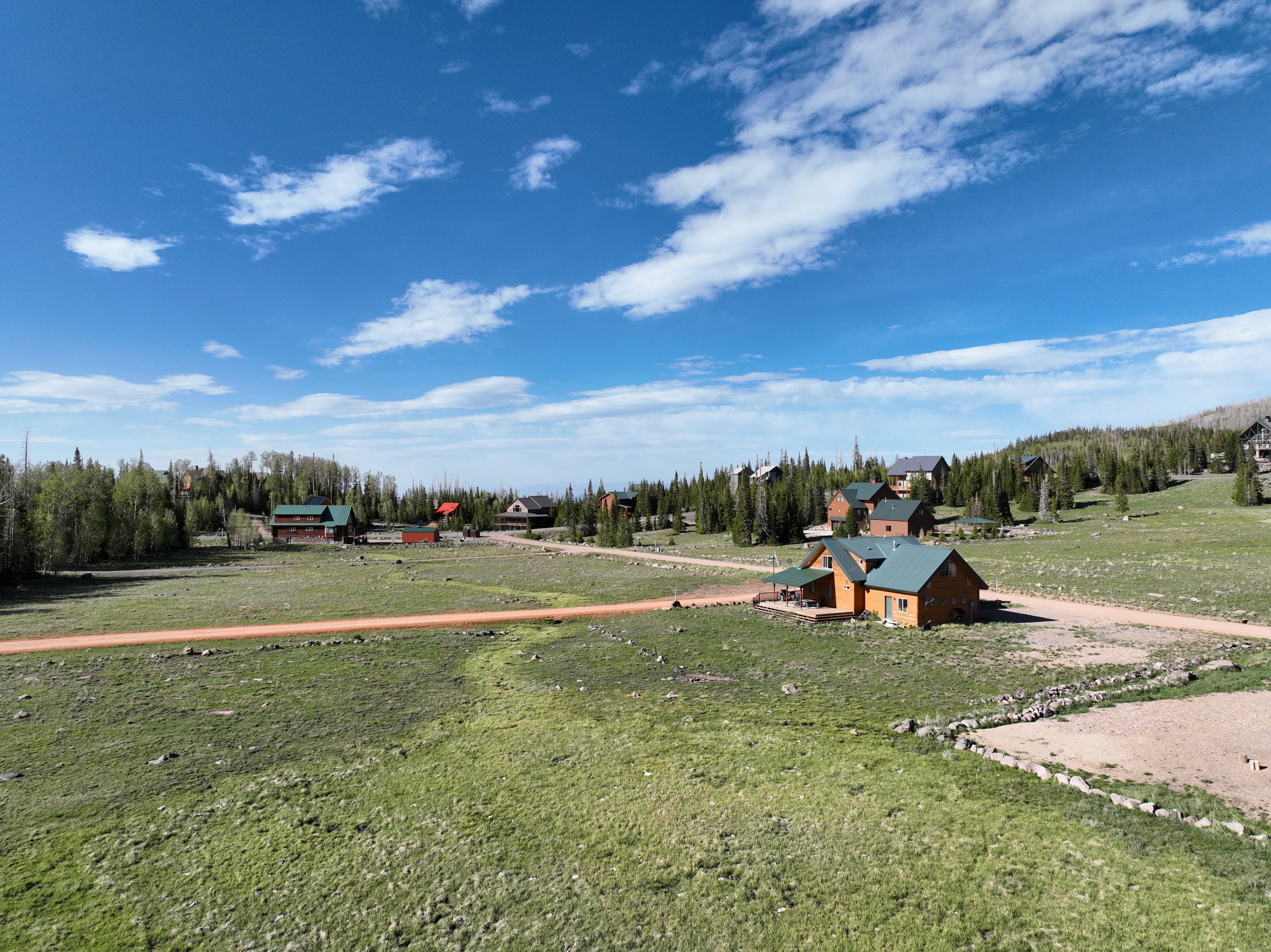 Expansive grassy terrain featuring a dirt road and scattered residences