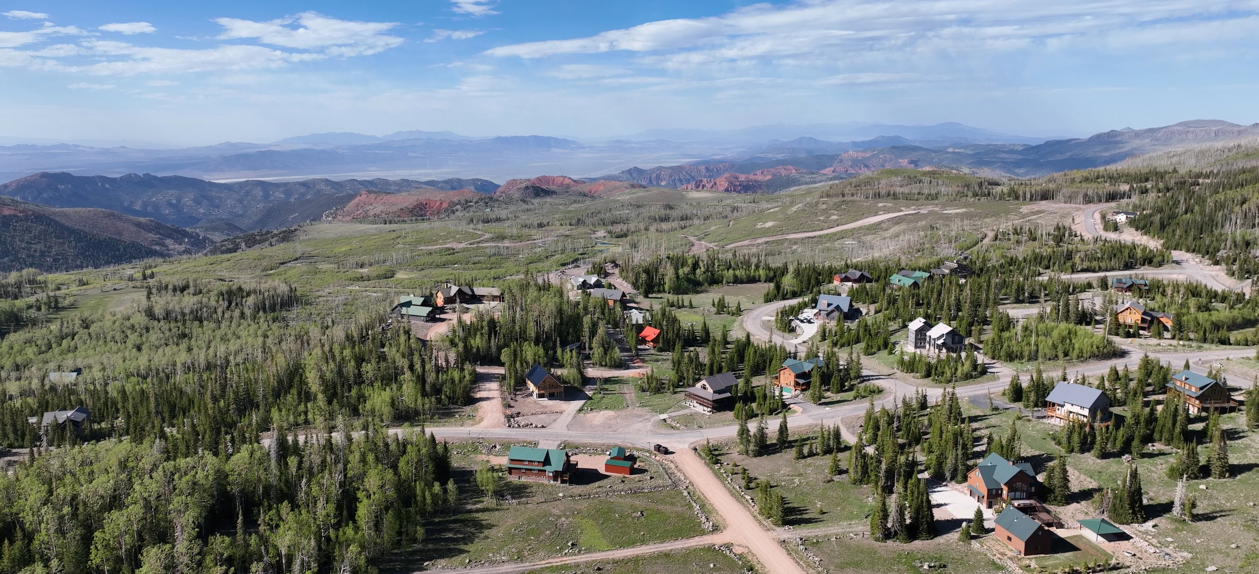 Mountain community featuring numerous cabins and residences amidst a forested landscape