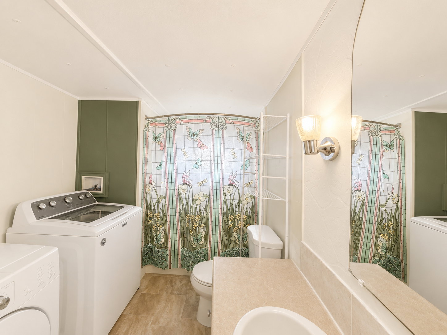 Full bathroom with tub/shower combination, vanity, large mirror, and laundry area.