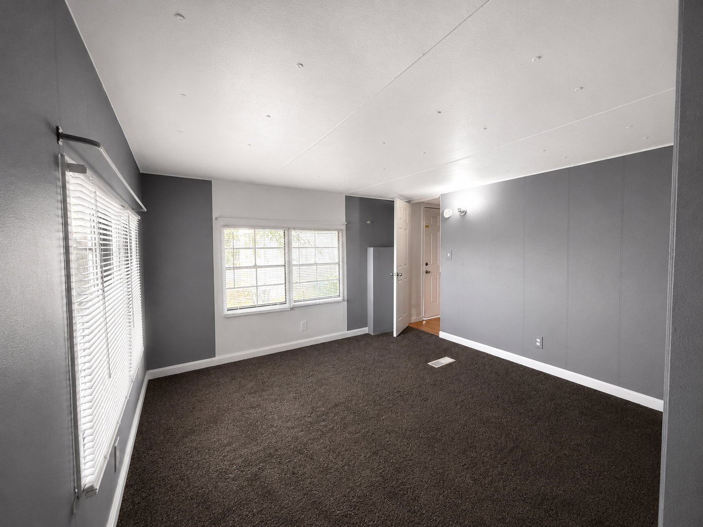 Bedroom view featuring natural light, neutral gray walls, and comfortable carpeted flooring.