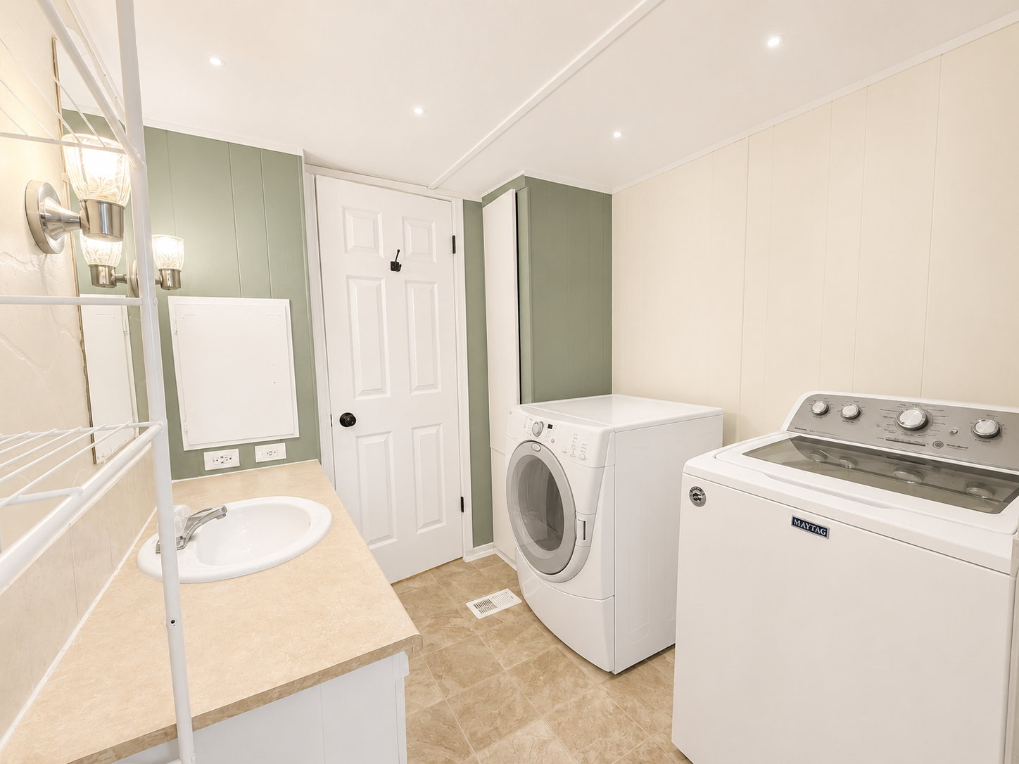 Combined bathroom and laundry room featuring washer and dryer, vanity, updated lighting, and convenient built-in storage.