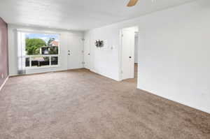 Spacious carpeted room featuring a large picture window, recessed lighting, and a neutral color palette