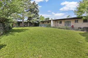 Expansive green lawn with mature trees and a chain-link fence