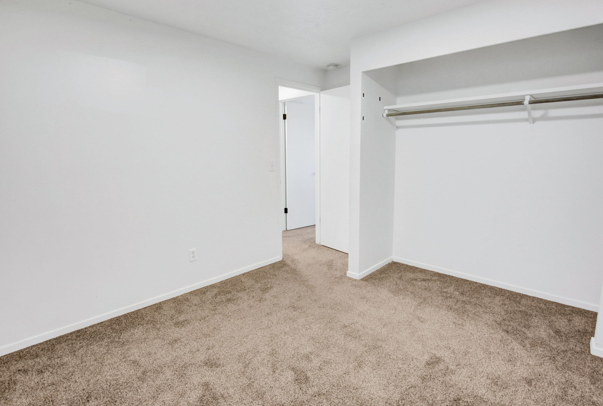 Carpeted room featuring white walls and a built-in closet with a hanging rod