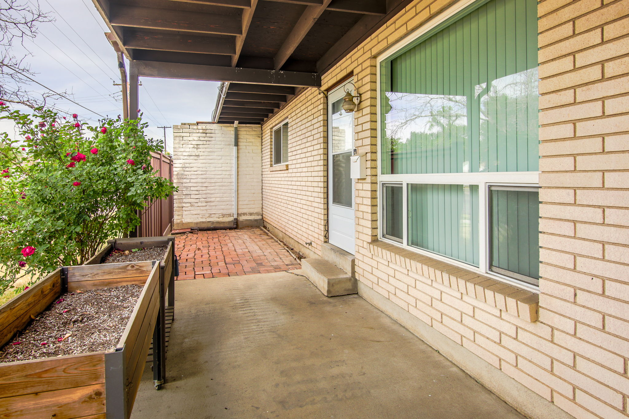 Covered patio area featuring concrete flooring and a wood beam ceiling