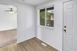 Entryway featuring wood-finish flooring, a white paneled door with brass hardware, and a window with blinds