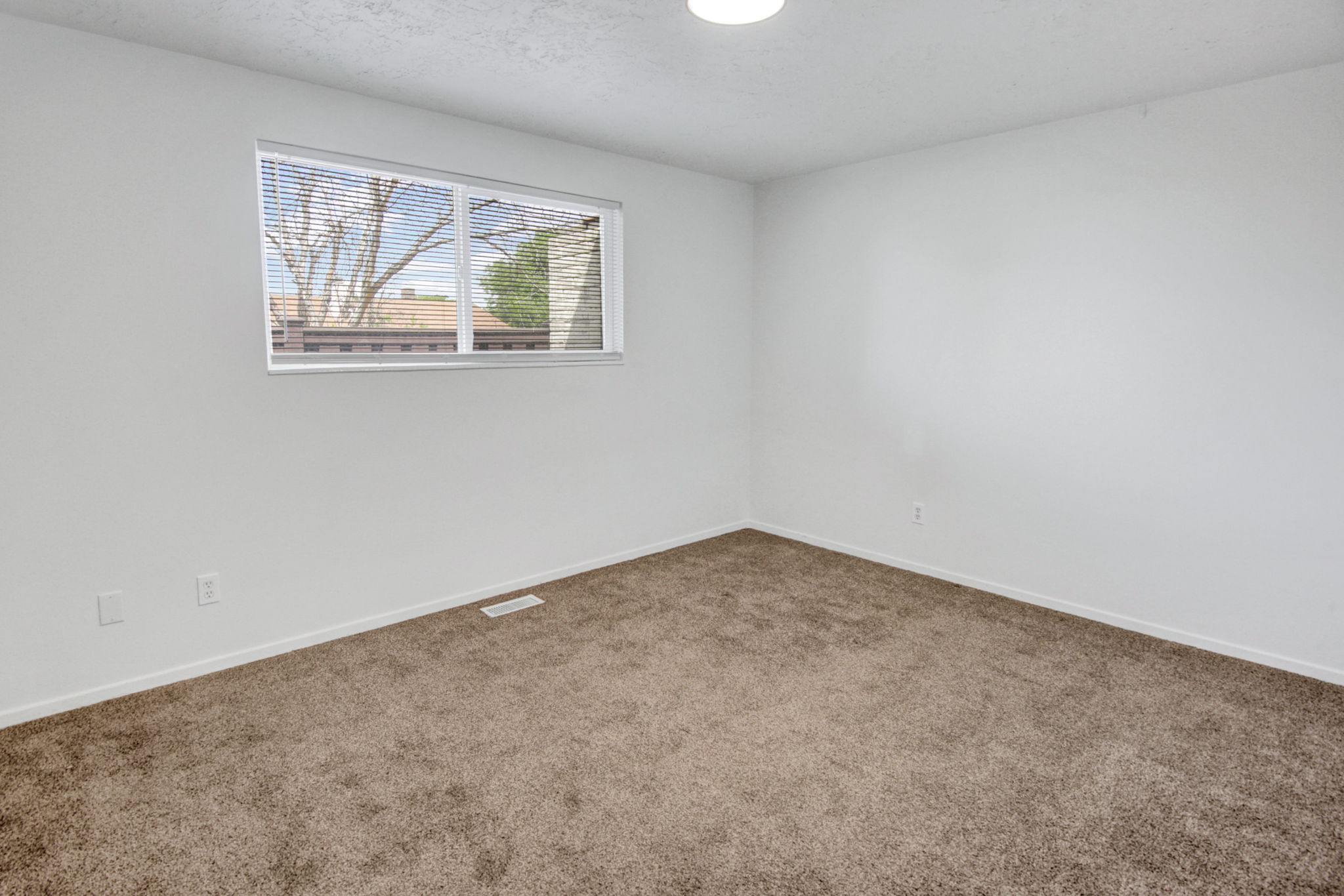 Interior room featuring light brown carpeting, white baseboards, and white walls