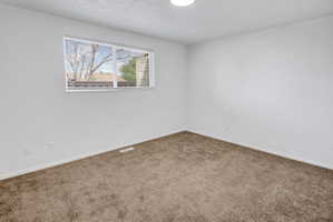 Interior room featuring light brown carpeting, white baseboards, and white walls