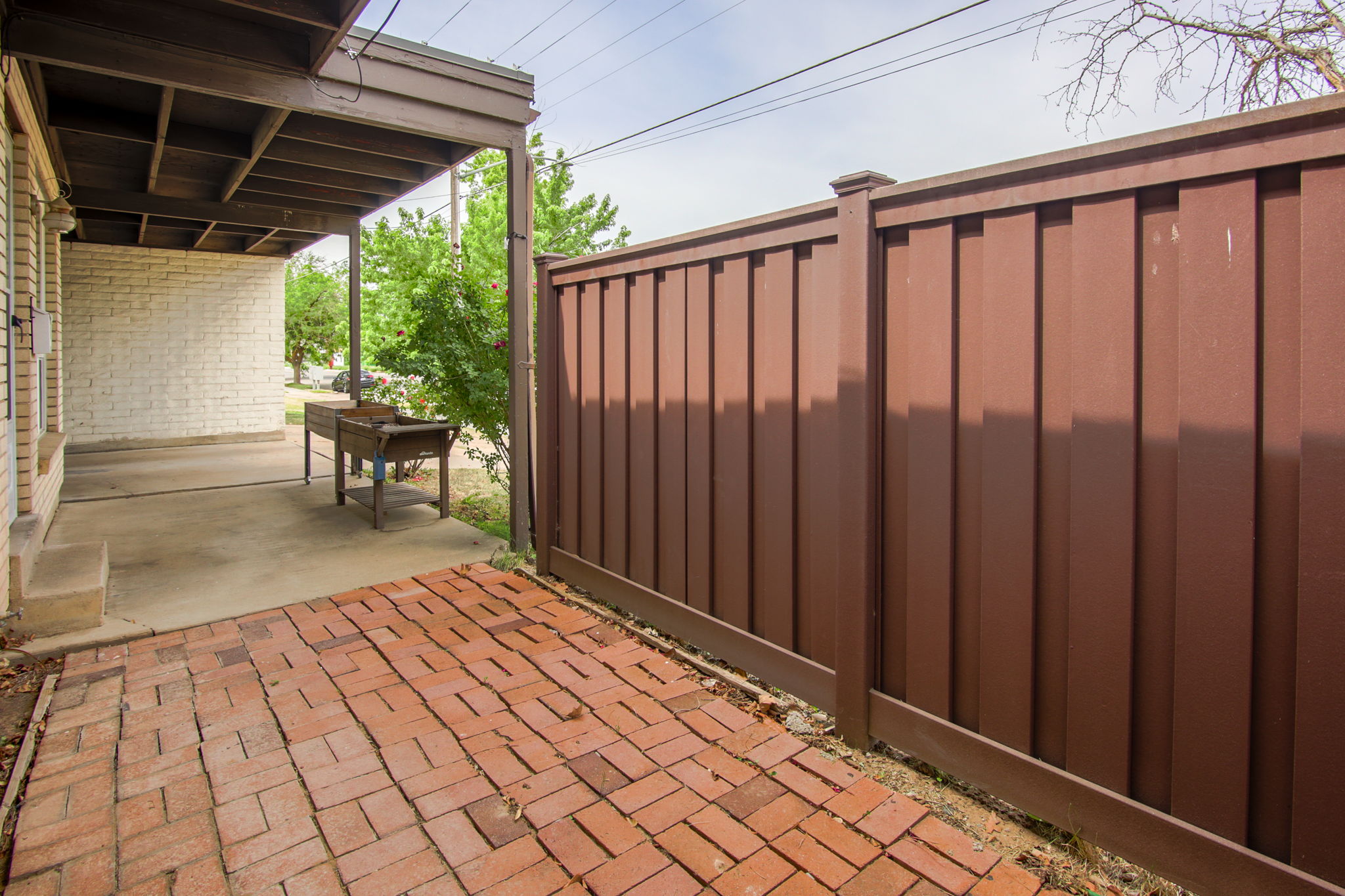 Covered patio area featuring a brick paver section and a solid privacy fence