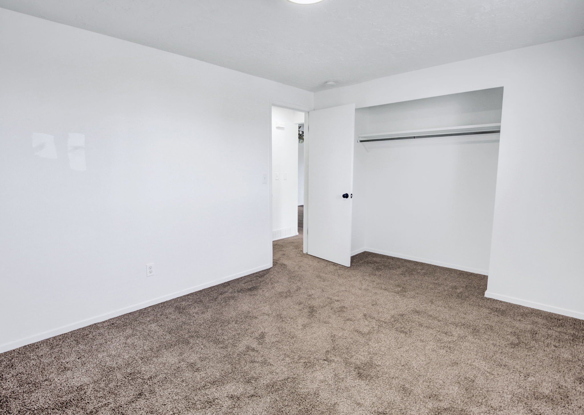 Carpeted room featuring a ceiling-mounted light fixture, white walls, and baseboards