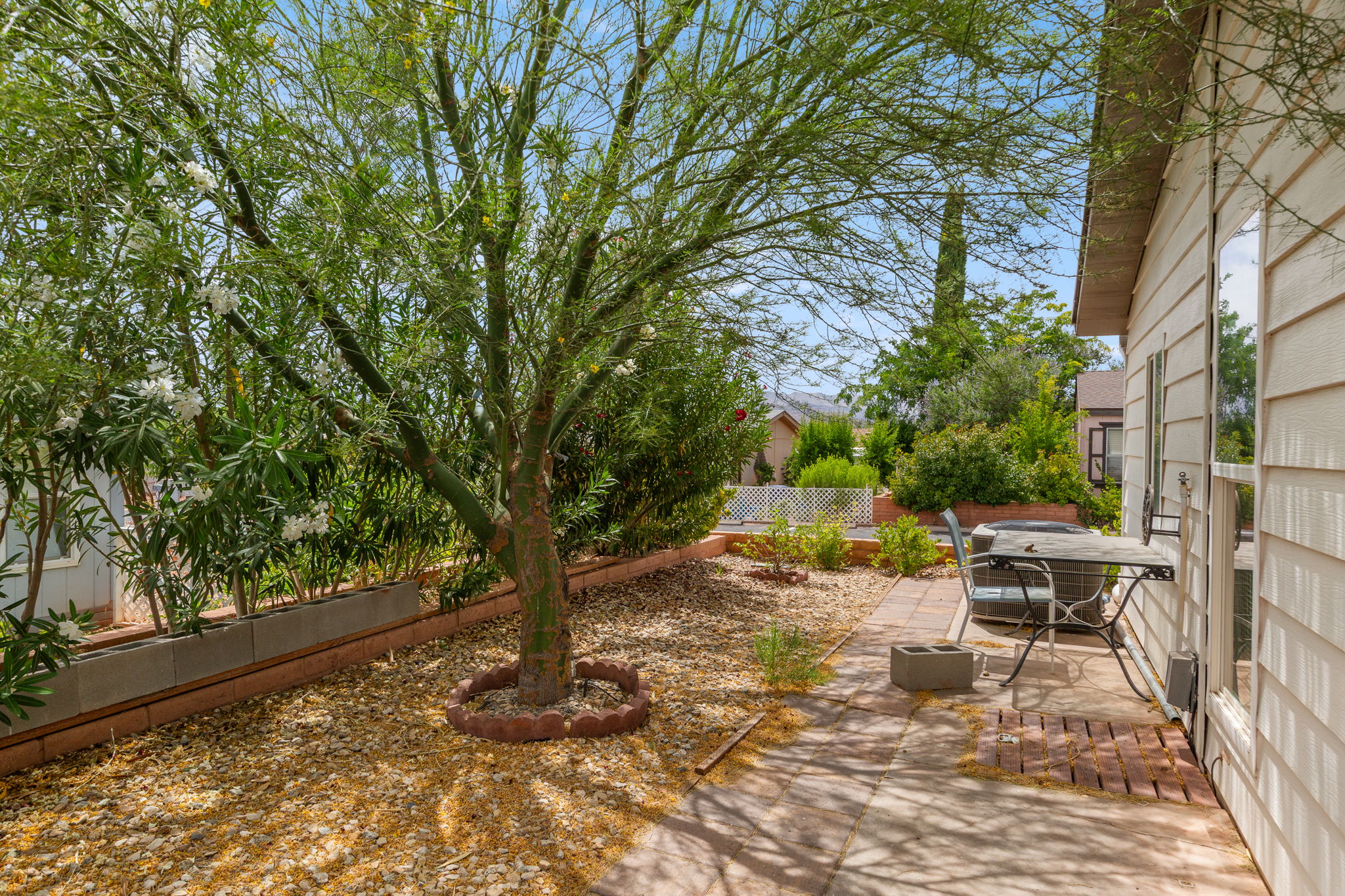 Side yard with a mature tree, gravel ground cover, and a paver patio