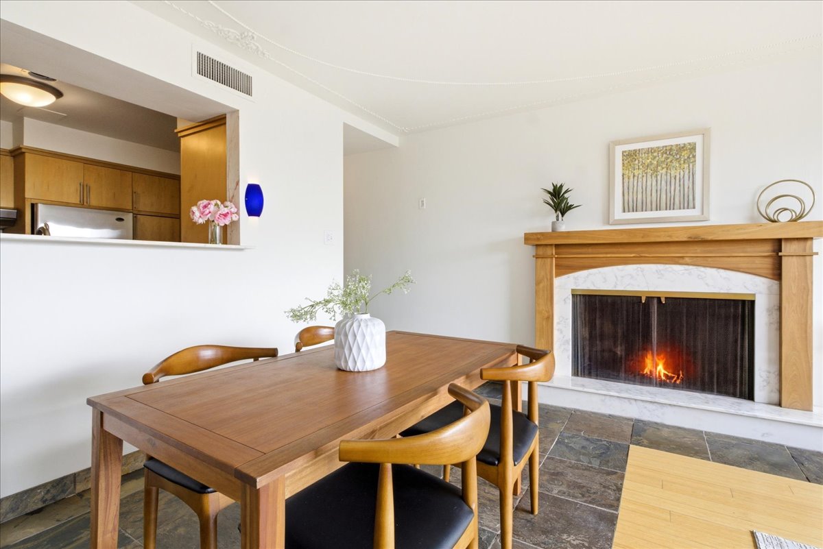 Dining area featuring a wood-finish table, stone tile flooring, and a fireplace with a wood-finish mantel and marble surround