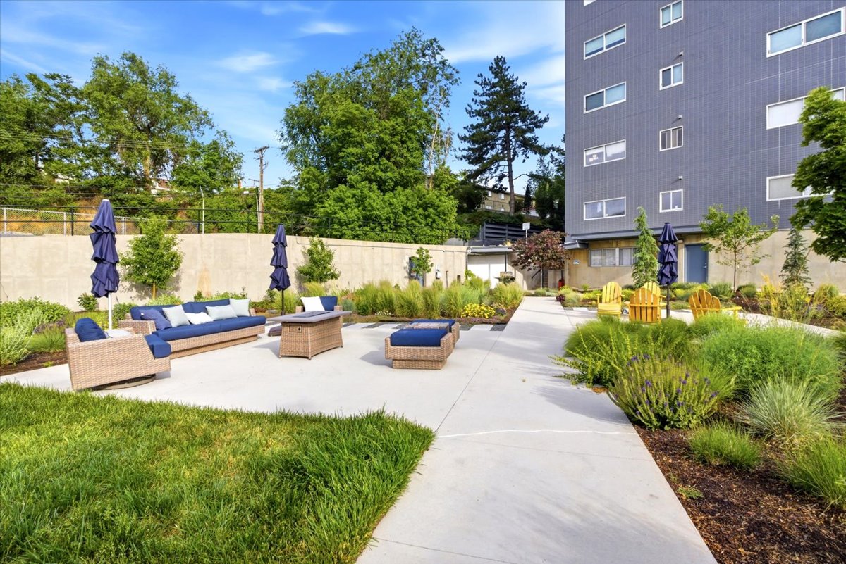 Expansive outdoor patio area featuring concrete paving, integrated landscaping, and a substantial retaining wall