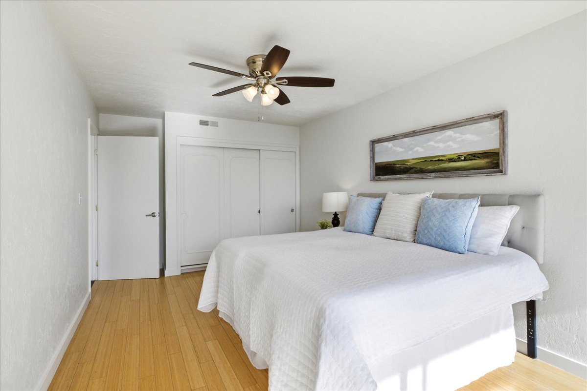 Spacious room featuring wood-finish flooring, a ceiling fan with integrated lighting, and a closet with white sliding doors