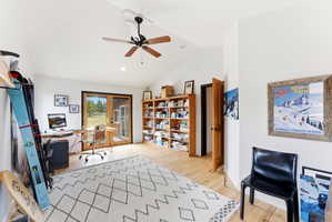 Vaulted ceiling with a ceiling fan, light wood-finish flooring, built-in shelving, and French doors providing natural light